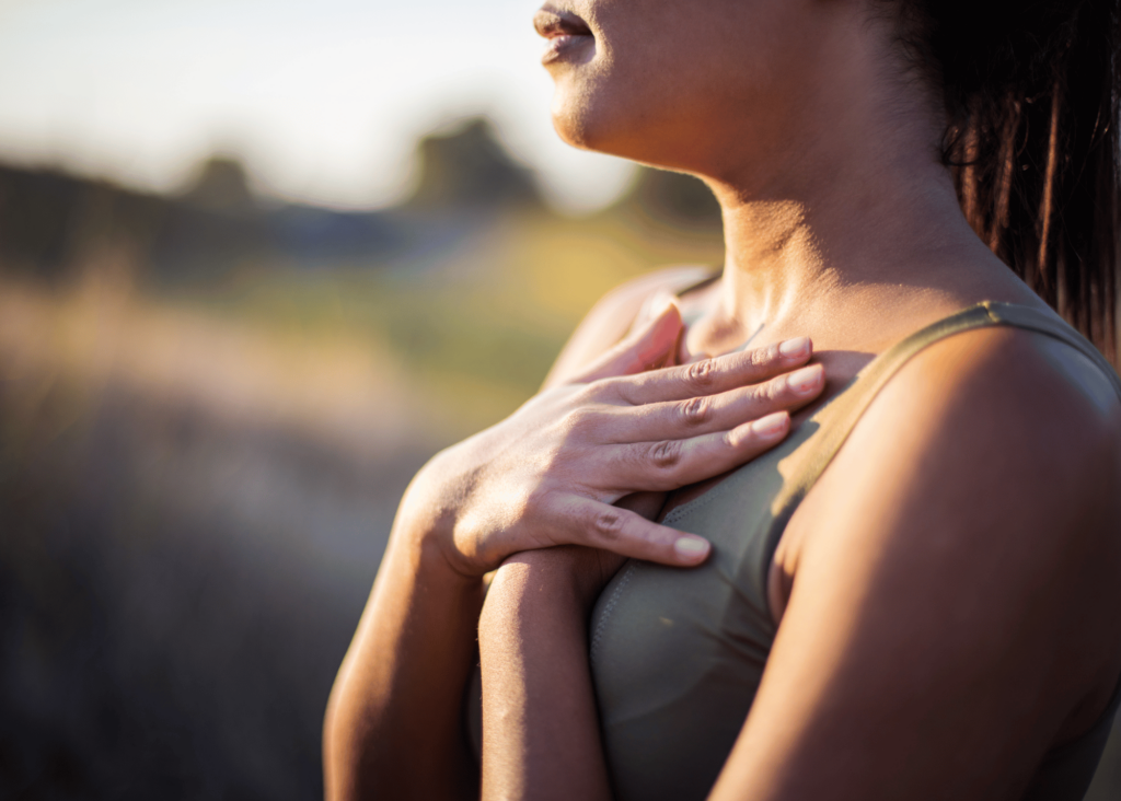 Side profile of a woman breathing with her hands on her chest, while using somatic practices to help with burnout.