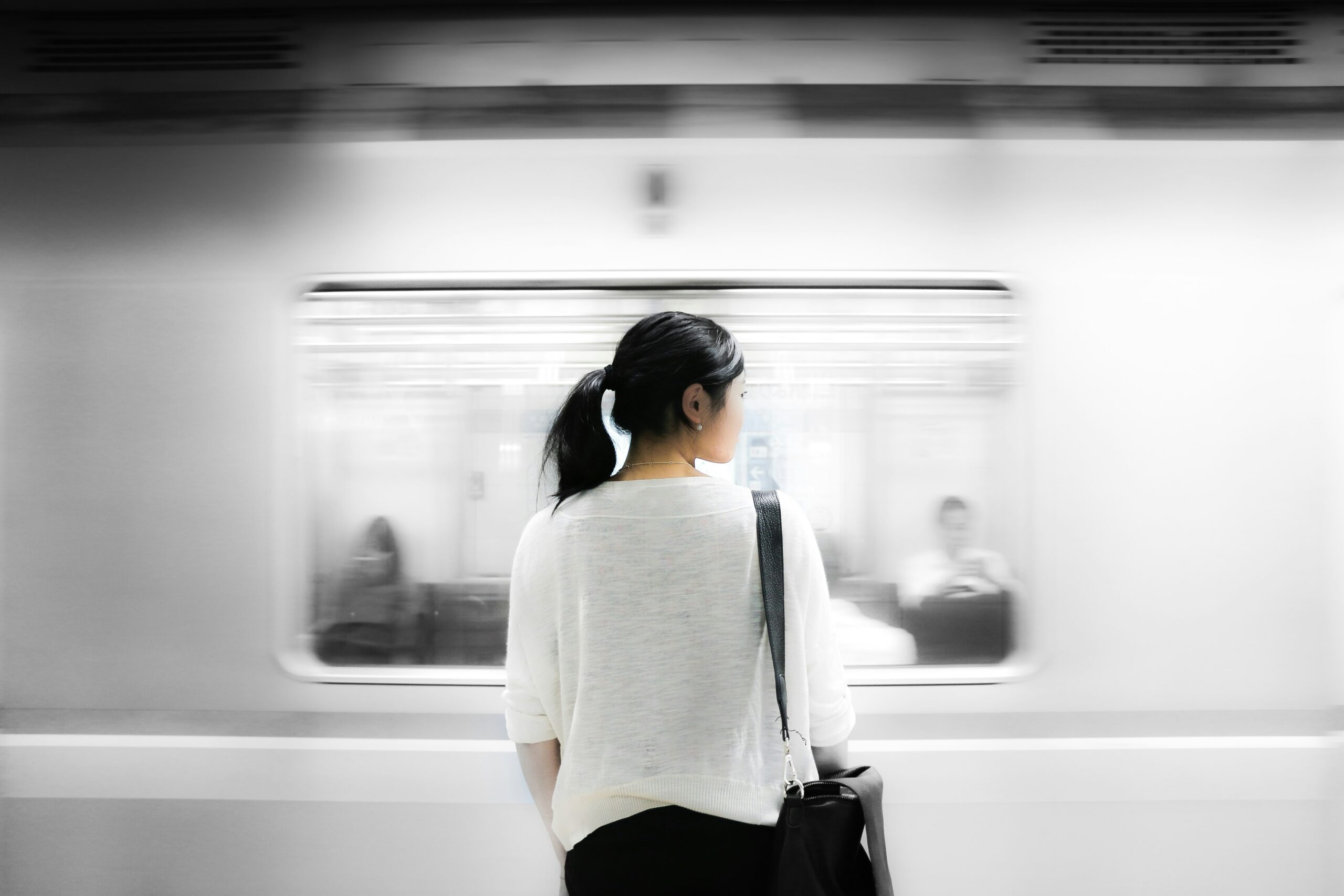 Asian woman watching subway train, and wondering "why am I so sensitive?"